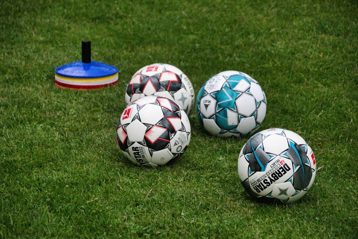 Fu&szlig;b&auml;lle und Trainingsh&uuml;tchen auf Rasen