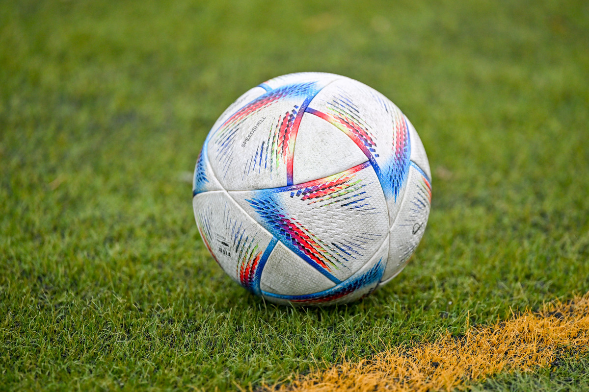 Fu&szlig;ball auf Rasen neben gelber Markierungslinie