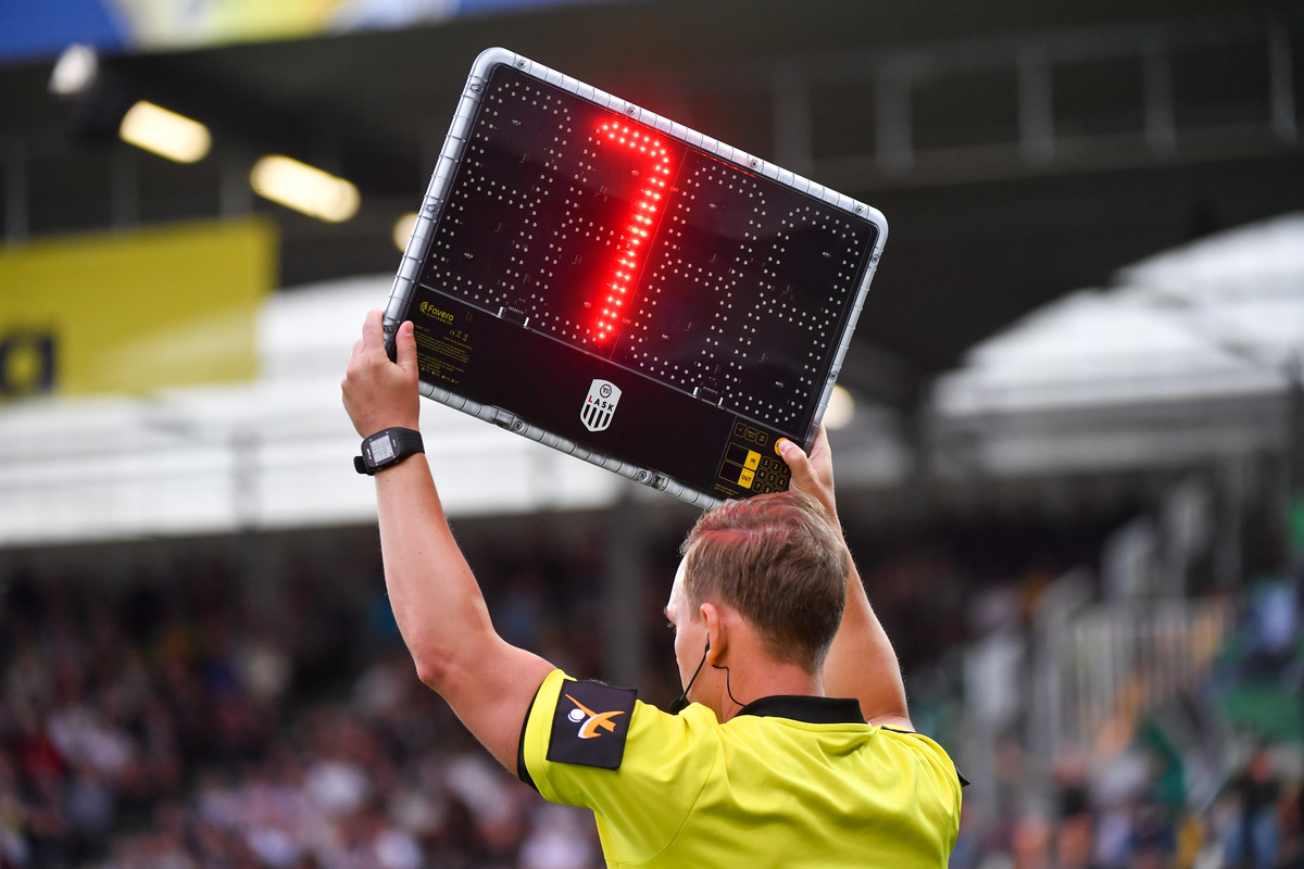 Mann h&auml;lt Anzeigetafel, die eine Nachspielzeit von sieben Minuten anzeigt