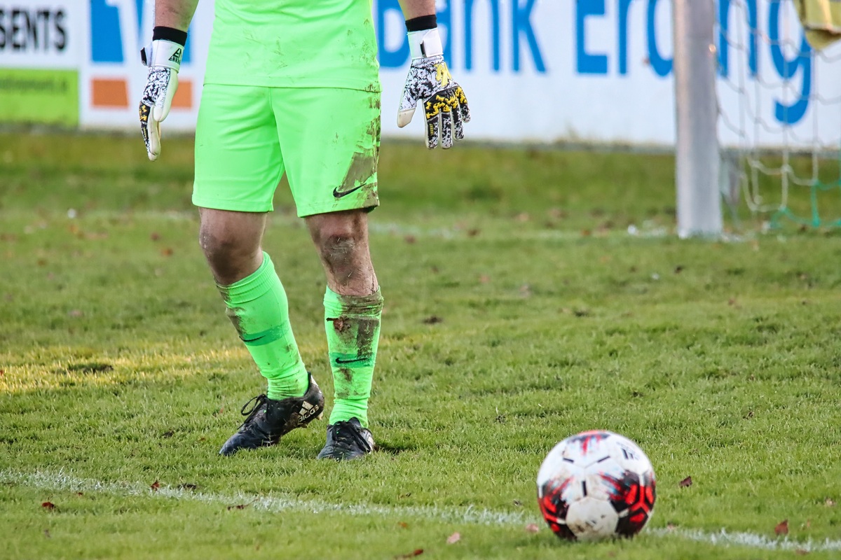 Torwart in Neongr&uuml;n, im Vordergrund der Ball