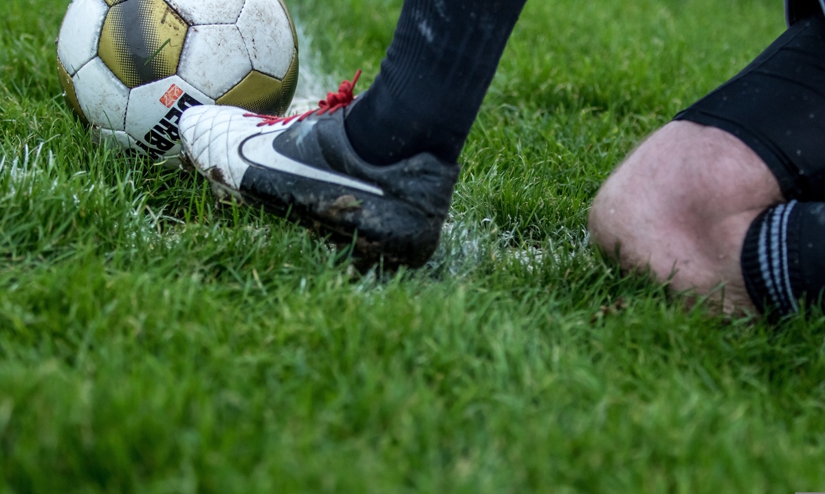 Spieler rutscht mit Ball auf Rasen